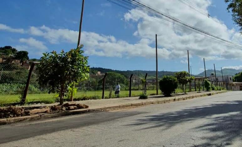 Vista da Arena Coqueiros a partir da avenida, com o campo cercado e a calçada